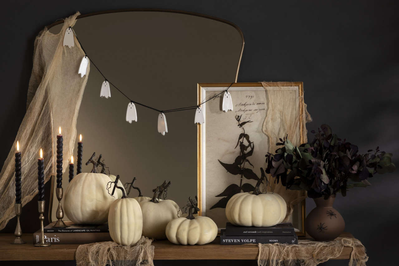 décor halloween sur console bois avec guirlande fantome, bougie noire, courge citrouille blanche chandeliers