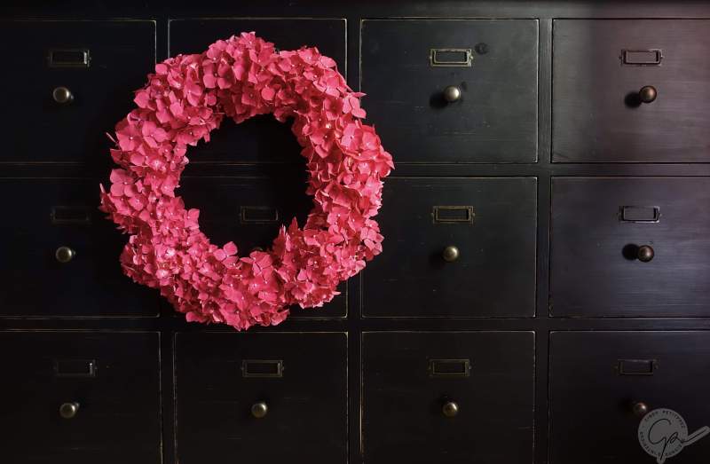 couronne de fleurs fraiches en hortensias rose sur meuble de métier noir