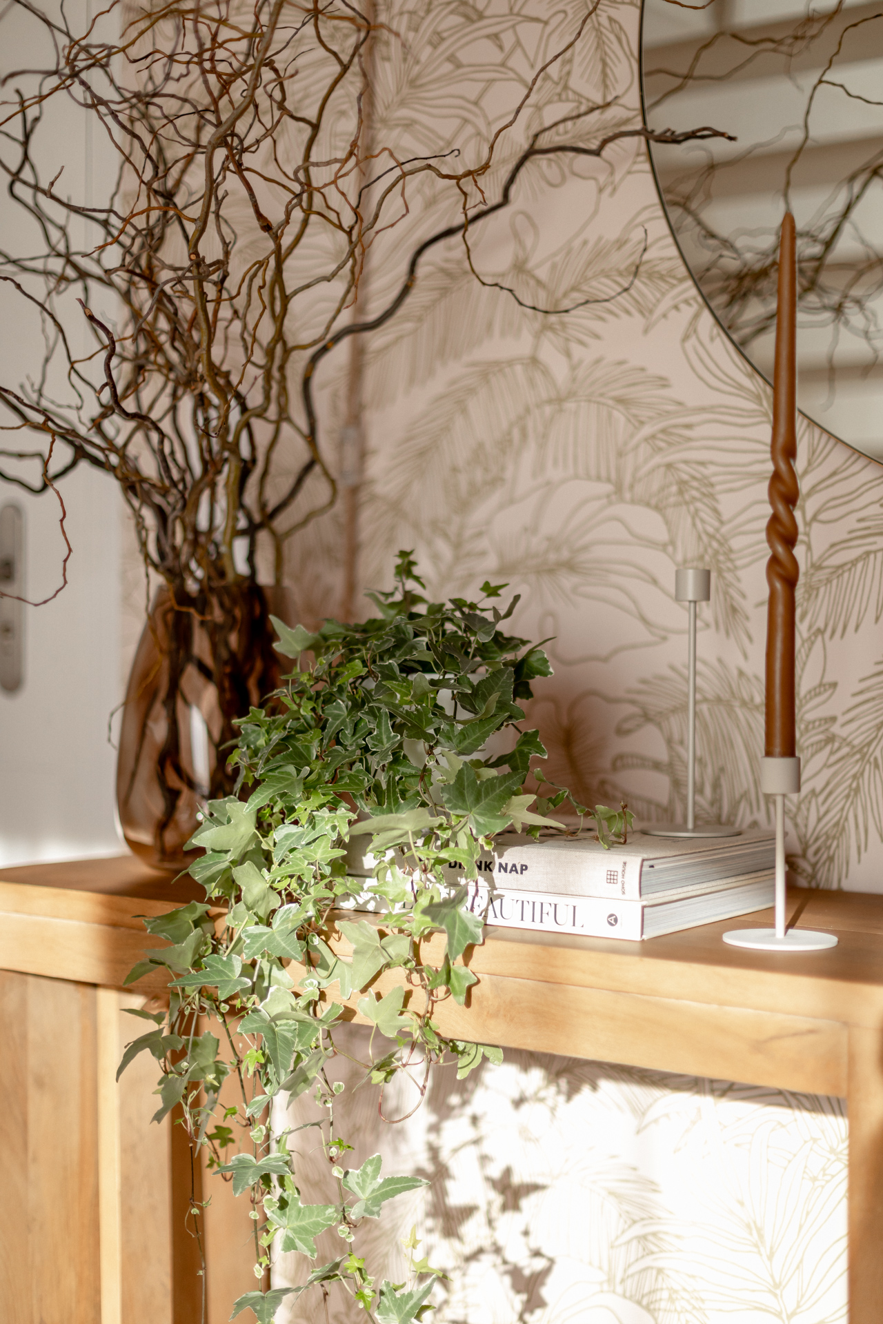 décoration console avec bougeoirs, bougie, plante lierre, livres déco et vase comprenant des branches