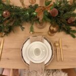 Décoration de la table de noel avec gaze de coton, couverts dorés, verre ambré, sapin, boules velours marrons, bougies