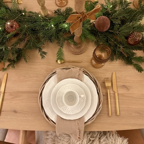 Décoration de la table de noel avec gaze de coton, couverts dorés, verre ambré, sapin, boules velours marrons, bougies